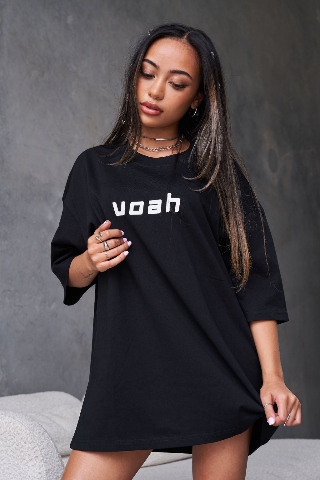 black oversized tee with the brand name 'voah' printed on the front and a paint splatter graphic design on the back.