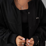 Black oversized French Terry overshirt with button detailing, paired with a black top and layered necklaces.