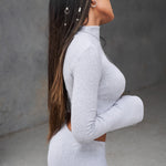 long sleeve grey crop top with a high neckline and bell sleeves.