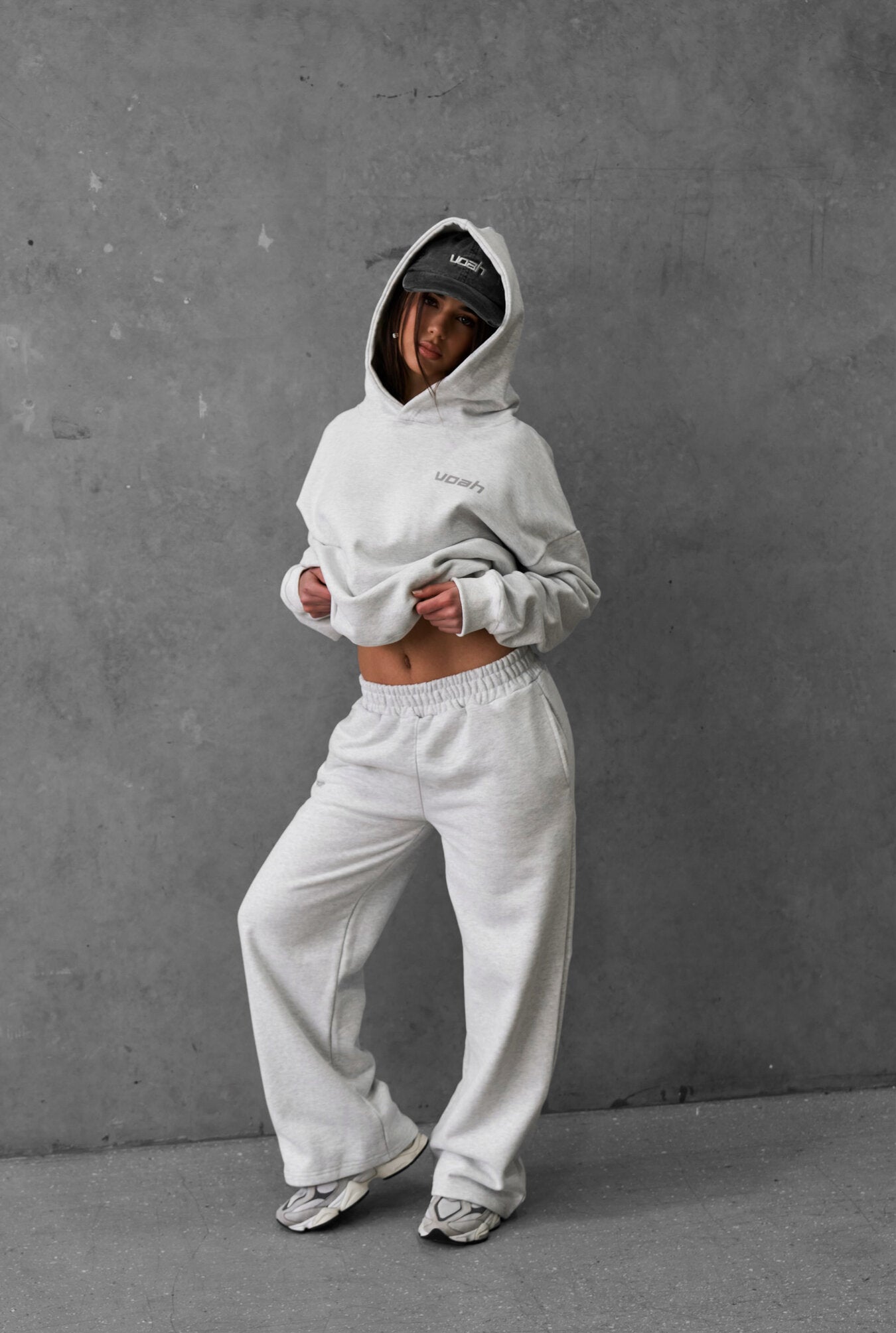 a girl wearing a grey hoodie and pants against a gray background